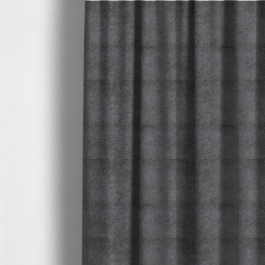 The fabric used to create these made-to-measure curtains is a deep, dark grey or graphite-toned upholstery fabric. It features the signature dense, uniform, boucle-style weave of the collection, composed of small, looped, and nubby yarn fibres that create a soft and tactile surface.