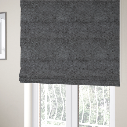 The fabric used to create these Roman blinds is a deep, dark grey or graphite-toned upholstery fabric. It features the signature dense, uniform, boucle-style weave of the collection, composed of small, looped, and nubby yarn fibres that create a soft and tactile surface.