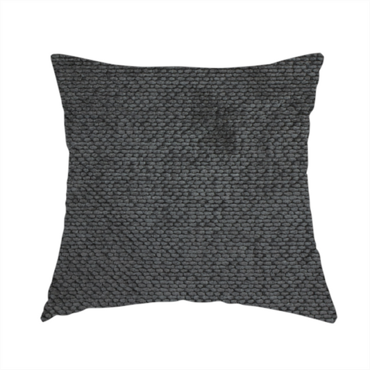 The fabric used to create this handmade cushion is a deep, dark charcoal or near-black upholstery fabric. It maintains the signature dense, uniform, boucle-style weave of the collection, characterized by small, looped, and nubby yarn fibres that provide a soft and tactile surface.