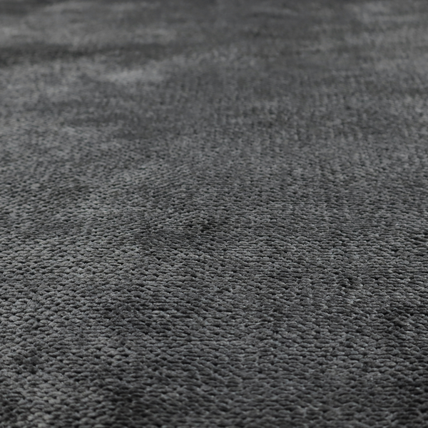 A deep, dark charcoal or near-black upholstery fabric. It maintains the signature dense, uniform, boucle-style weave of the collection, characterized by small, looped, and nubby yarn fibres that provide a soft and tactile surface.