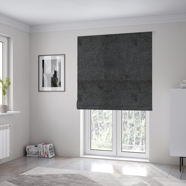 The fabric used to create these Roman blinds is a deep, dark charcoal or near-black upholstery fabric. It maintains the signature dense, uniform, boucle-style weave of the collection, characterized by small, looped, and nubby yarn fibres that provide a soft and tactile surface.