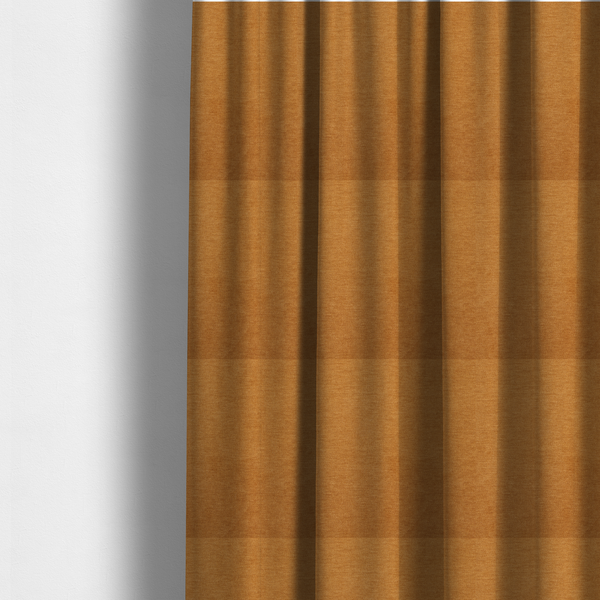 The fabric used to create these made-to-measure curtains is a solid orange or mustard yellow woven textile with a fine, subtle textured weave.