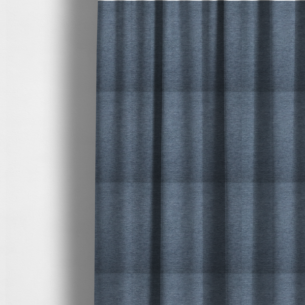 The fabric used to create these made-to-measure curtains is solid light blue or steel blue woven textile with a fine, subtle textured weave.