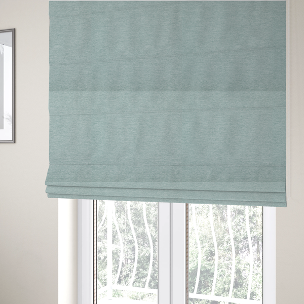 The fabric used to create these Roman blinds is a solid pale aqua or mint green woven textile with a fine, subtle textured weave.