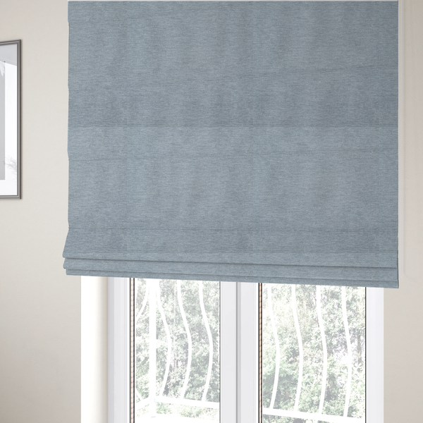 The fabric used to create these Roman blinds is a solid light periwinkle woven fabric swatch with a fine, subtle texture.