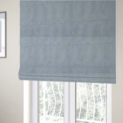 The fabric used to create these Roman blinds is a solid light periwinkle woven fabric swatch with a fine, subtle texture.