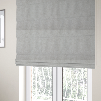 The fabric used to create these Roman blinds is a light grey or silver woven textile with a fine, subtle textured weave.