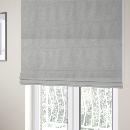 The fabric used to create these Roman blinds is a light grey or silver woven textile with a fine, subtle textured weave.