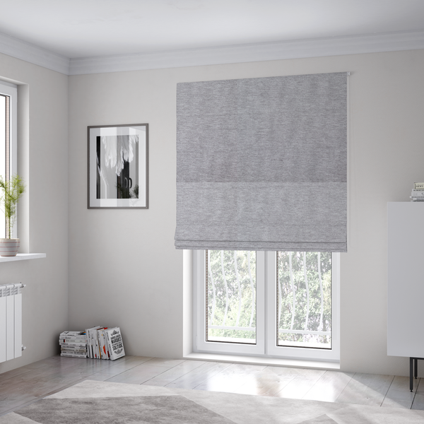 The fabric used to create these Roman blinds is a medium grey or silver-grey woven textile with a fine, subtle textured weave.