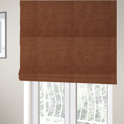 The fabric used to create these Roman blinds is a textured, rich rust or burnt orange woven upholstery fabric.