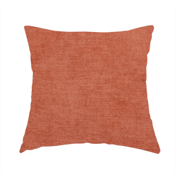 The fabric used to create this handmade cushion is a textured, vibrant burnt orange or coral-coloured woven upholstery fabric.