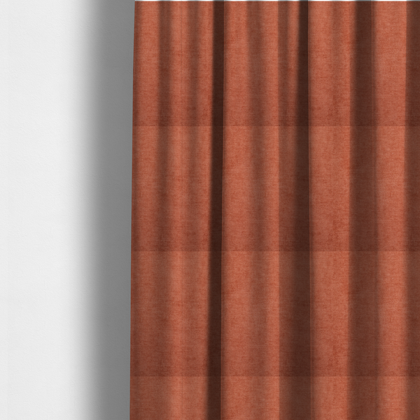 The fabric used to create these made-to-measure curtains is a textured, vibrant burnt orange or coral-coloured woven upholstery fabric.