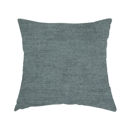 The fabric used to create this handmade cushion is a textured, grey-blue or muted teal woven upholstery fabric.