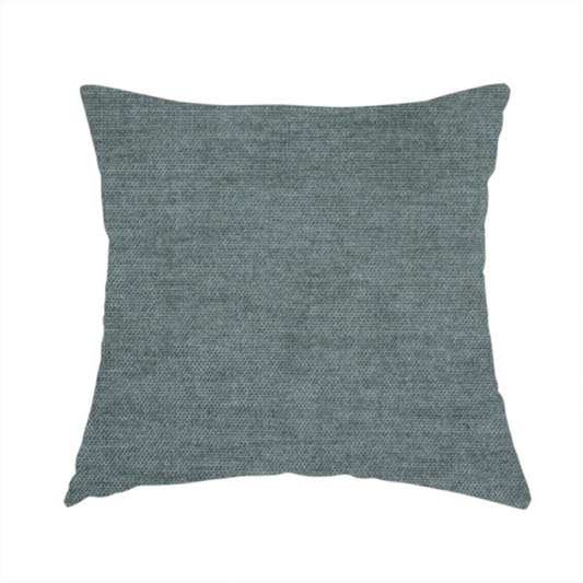 The fabric used to create this handmade cushion is a textured, grey-blue or muted teal woven upholstery fabric.