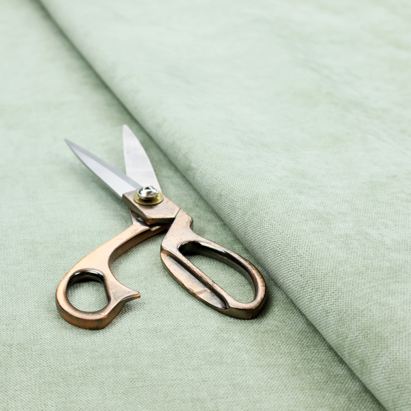 A textured, light mint green or pale sage green woven upholstery fabric.
