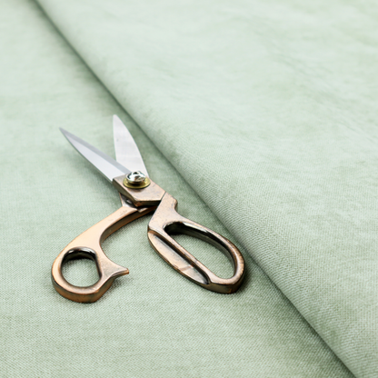 A textured, light mint green or pale sage green woven upholstery fabric.