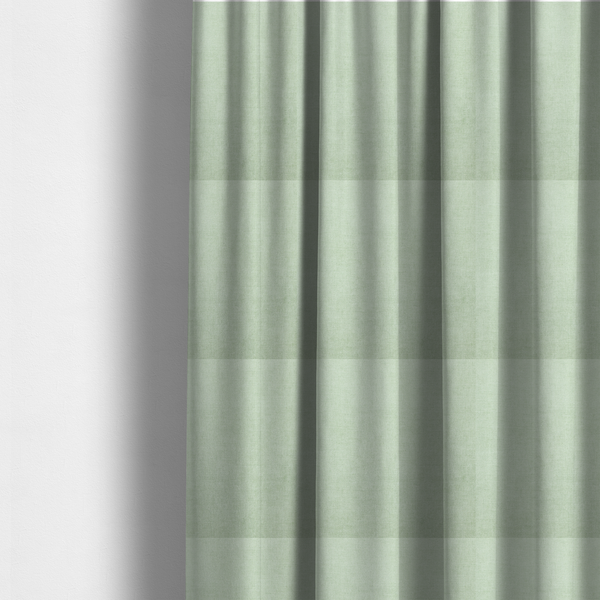 The fabric used to create these made-to-measure curtains is a textured, light mint green or pale sage green woven upholstery fabric.