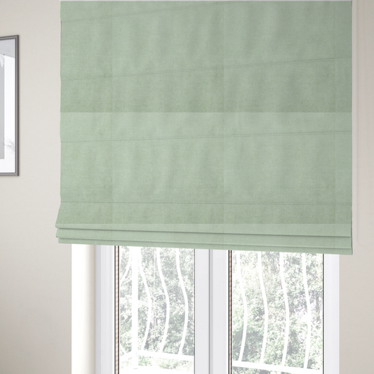 The fabric used to create these Roman blinds is a  textured, light mint green or pale sage green woven upholstery fabric.