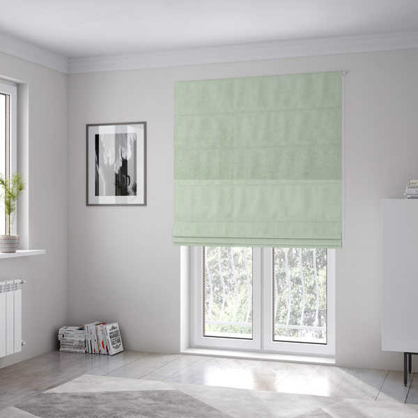 The fabric used to create these Roman blinds is a  textured, light mint green or pale sage green woven upholstery fabric.