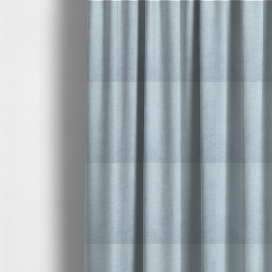The fabric used to create these made-to-measure curtains is a textured, light blue or pale sky blue woven upholstery fabric.