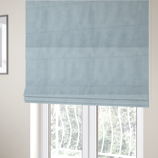 The fabric used to create these Roman blinds is a textured, light blue or pale sky blue woven upholstery fabric.