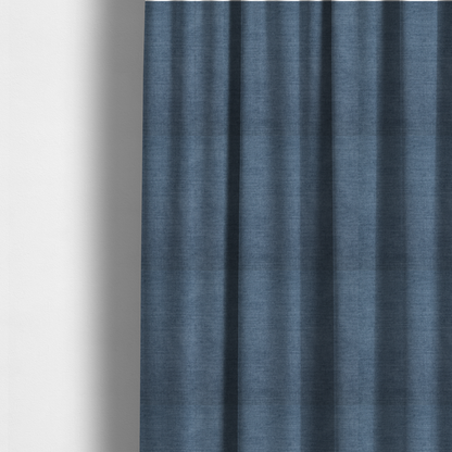 The fabric used to create these made-to-measure curtains is a textured, denim blue or dusty blue woven upholstery fabric.
