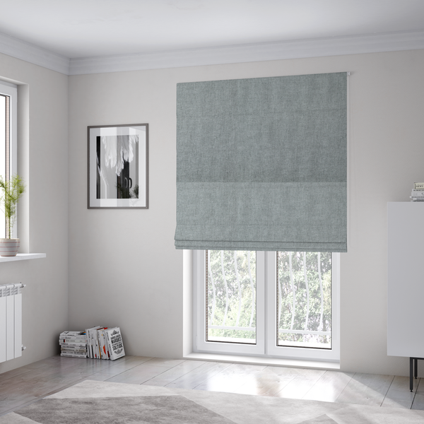 The fabric used to create these Roman blinds is a  textured, light grey or silver grey woven upholstery fabric.
