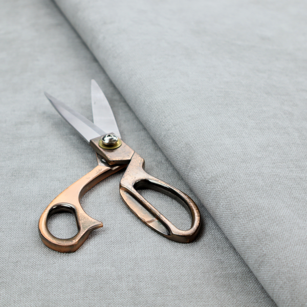 A textured, very light grey or off-white woven upholstery fabric.