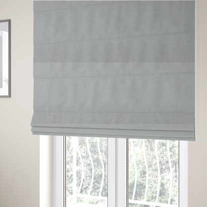 The fabric used to create these Roman blinds is a textured, very light grey or off-white woven upholstery fabric.
