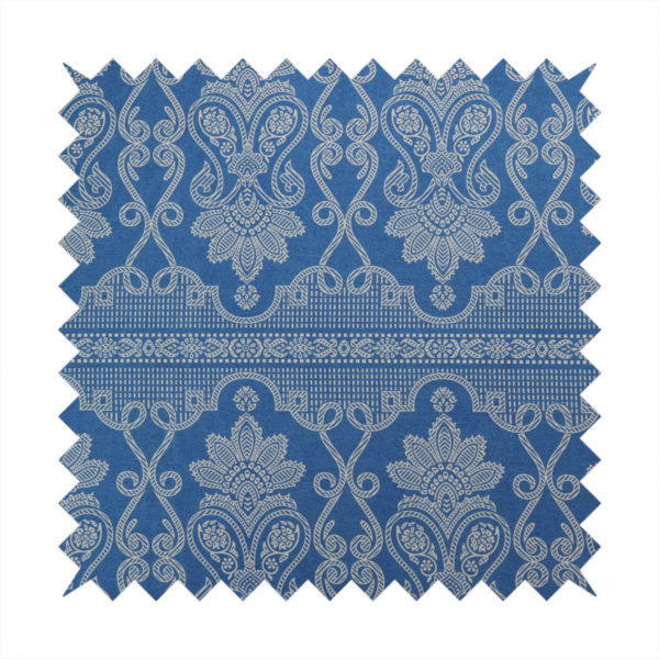 An ornate, traditional damask upholstery fabric on a rich blue background featuring intricate cream-coloured symmetrical floral and paisley motifs divided horizontally by a decorative lattice and scroll border.   