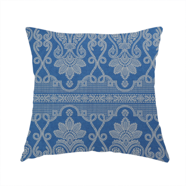 The fabric used to create this handmade cushion is an ornate, traditional damask upholstery fabric on a rich blue background featuring intricate cream-coloured symmetrical floral and paisley motifs divided horizontally by a decorative lattice and scroll border.   