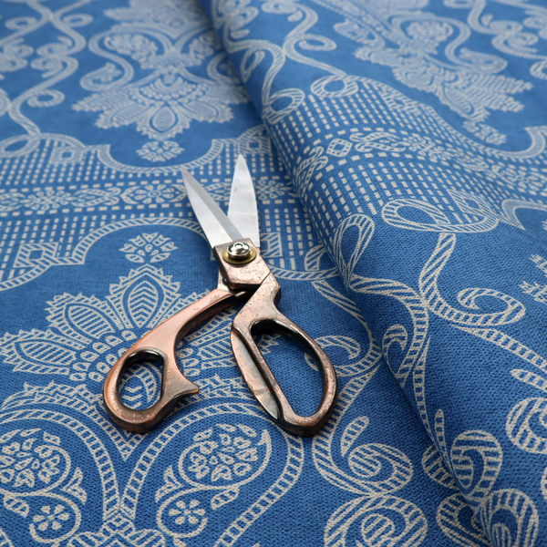 An ornate, traditional damask upholstery fabric on a rich blue background featuring intricate cream-coloured symmetrical floral and paisley motifs divided horizontally by a decorative lattice and scroll border.   