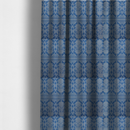 The fabric used to create these made-to-measure curtains is an ornate, traditional damask upholstery fabric on a rich blue background featuring intricate cream-coloured symmetrical floral and paisley motifs divided horizontally by a decorative lattice and scroll border.   