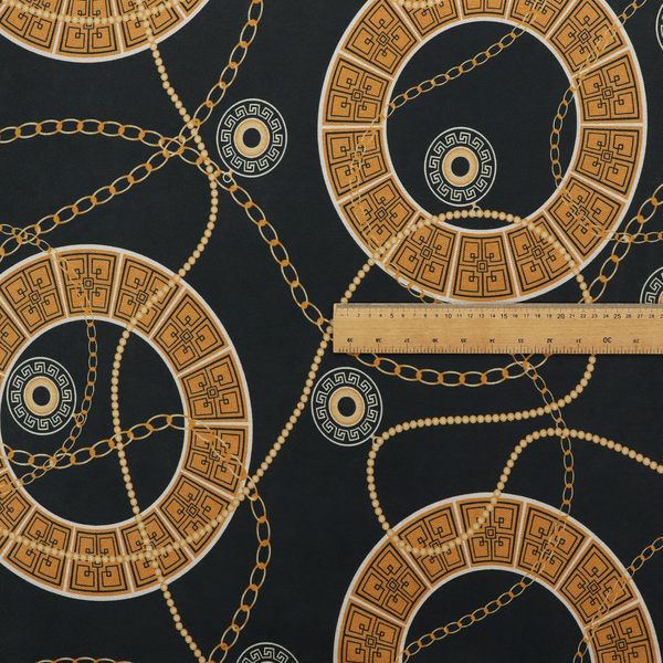 A glamorous luxury-style upholstery fabric on a black background featuring a repeating pattern of large gold-and-white patterned circular rings interconnected by dangling gold chains and small black-and-white geometric medallions.   