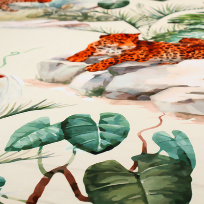 A tropical fabric pattern featuring leopards lounging on rocks amidst lush green foliage, palm fronds, and vibrant orange birds against a light background.