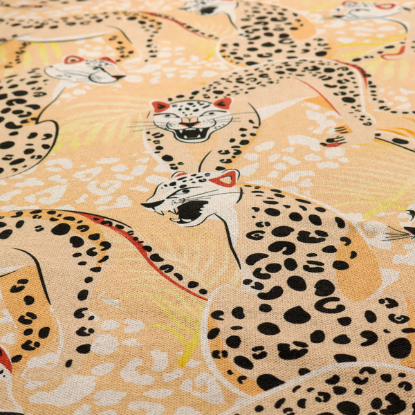 A playful patterned fabric featuring illustrated leopards in various poses with black spots and red-tipped ears, set against a warm yellow and beige jungle foliage background.   