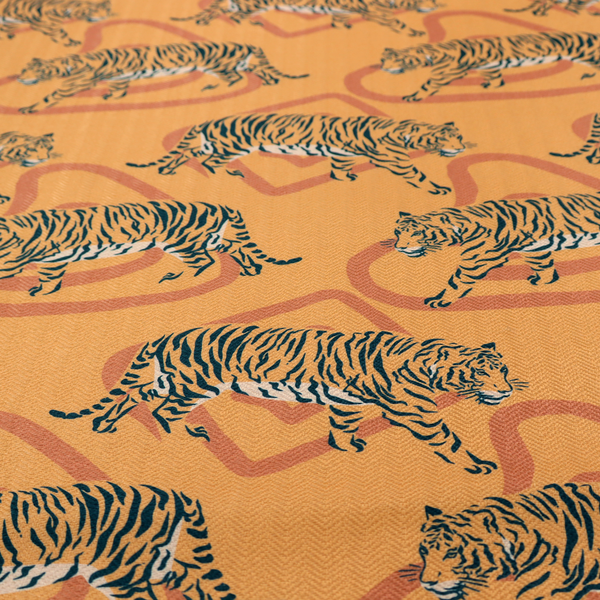 A striking upholstery fabric on a warm mustard-yellow background featuring a repeating pattern of prowling tigers in black stripes over abstract terracotta-coloured organic shapes.   