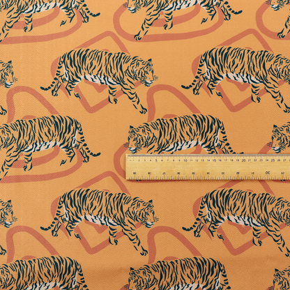 A striking upholstery fabric on a warm mustard-yellow background featuring a repeating pattern of prowling tigers in black stripes over abstract terracotta-coloured organic shapes.   