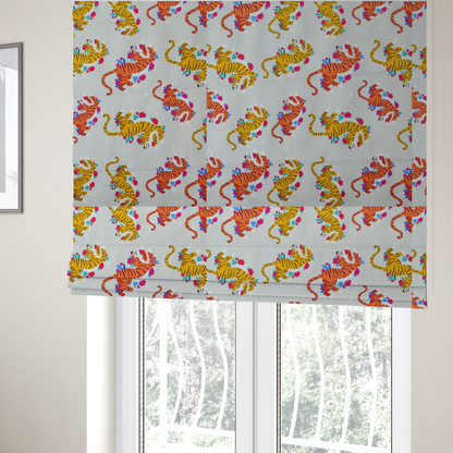 The fabric used to create these Roman blinds is a playful patterned fabric featuring whimsical leaping tigers in shades of orange and yellow, accented with colourful floral elements on a light grey background.   
