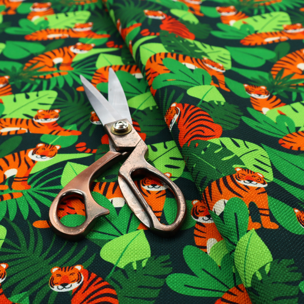 A vibrant jungle pattern fabric featuring orange and black tigers nestled among lush green tropical leaves and foliage against a dark background.   