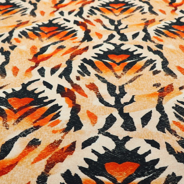 An abstract ikat fabric pattern featuring symmetrical, feather-like motifs in shades of burnt orange, cream, and dark charcoal black against a textured light background.   