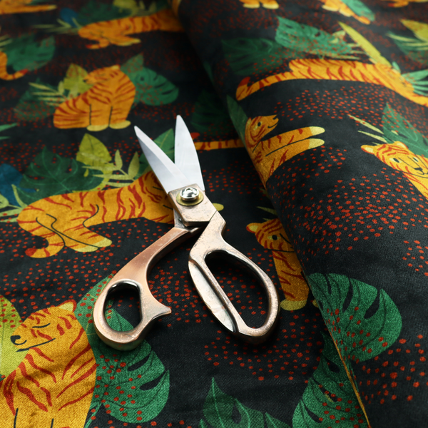 A vibrant fabric pattern featuring illustrated orange tigers in various poses surrounded by dark green tropical leaves and foliage against a dark background with red dotted accents.   