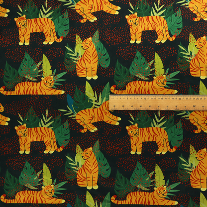 A vibrant fabric pattern featuring illustrated orange tigers in various poses surrounded by dark green tropical leaves and foliage against a dark background with red dotted accents.   