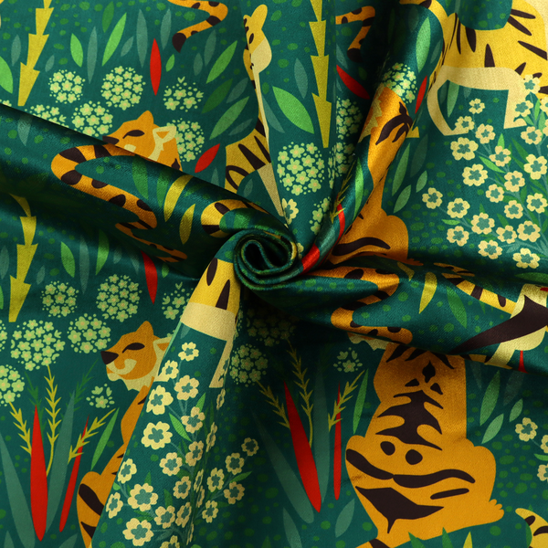 A detailed tropical jungle pattern fabric featuring illustrated yellow and black tigers, birds with red beaks, palm trees, and small white flowers on a deep green background.   