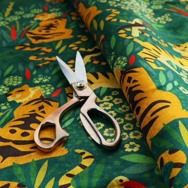 A detailed tropical jungle pattern fabric featuring illustrated yellow and black tigers, birds with red beaks, palm trees, and small white flowers on a deep green background.   