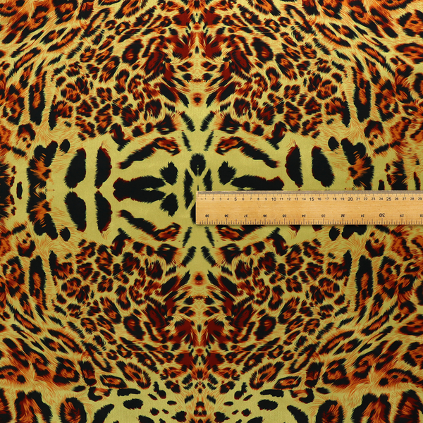 A bold, symmetrical leopard print fabric featuring a repeating kaleidoscope pattern of black and golden-brown rosettes on a warm yellow-gold background.
