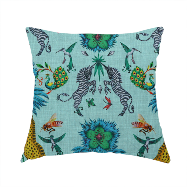 The fabric used to create this handmade cushion is an enchanting turquoise-toned fabric pattern featuring zebras, giraffes, hummingbirds, peacocks, bees, and mystical blue flowers with eye motifs on a light aqua background.