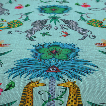 An enchanting turquoise-toned fabric pattern featuring zebras, giraffes, hummingbirds, peacocks, bees, and mystical blue flowers with eye motifs on a light aqua background.