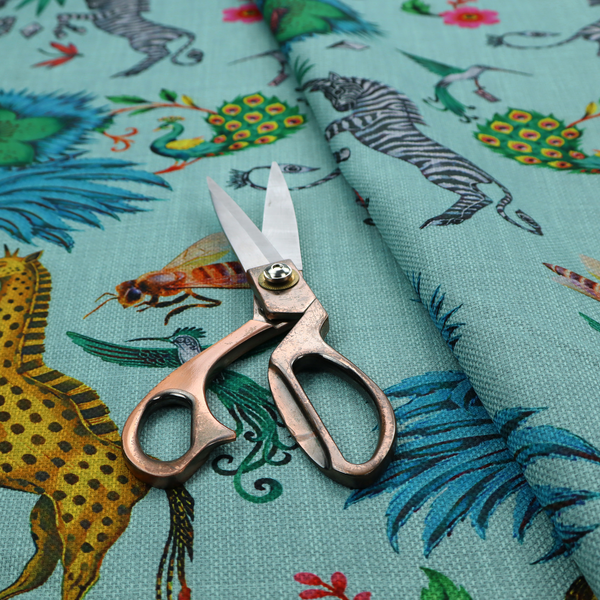 An enchanting turquoise-toned fabric pattern featuring zebras, giraffes, hummingbirds, peacocks, bees, and mystical blue flowers with eye motifs on a light aqua background.