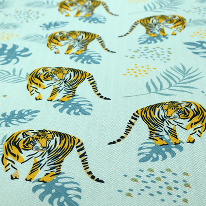 A tropical jungle upholstery fabric on a light mint-blue background featuring a repeating pattern of yellow and black tigers surrounded by teal monstera leaves, palm fronds, and yellow dot clusters.   
